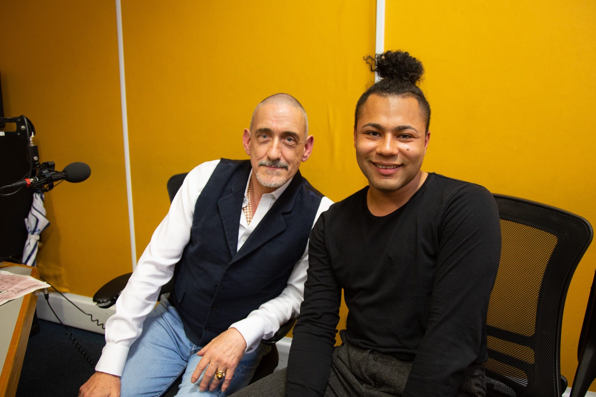 Travis Alabanza and Neil Bartlett sit beside each other in a radio recording studio