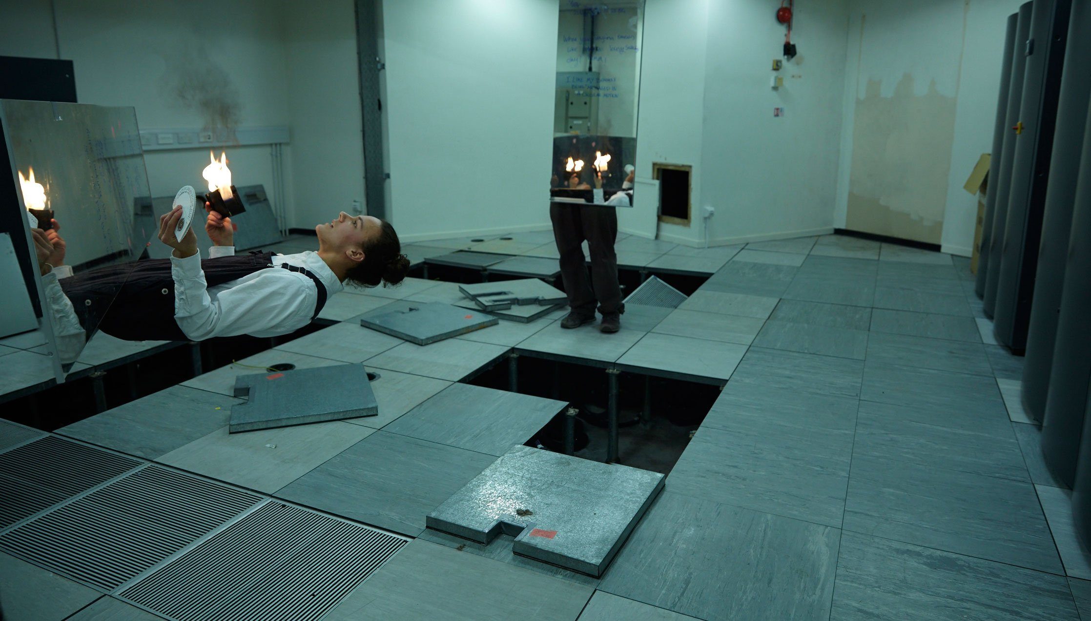 The artist has separated his torso, arms and head, from his legs using mirrors and digital manipulation. He holds flames in his hands.