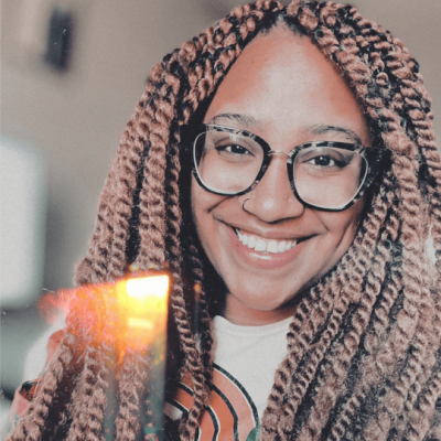 Jodie Worton is a smiley Black woman, who is wearing black glasses and a white t-shirt